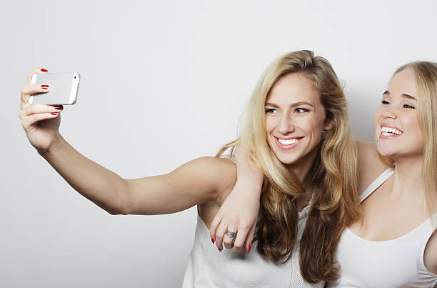 istock two young women taking selfie with mobile phone 2245652680