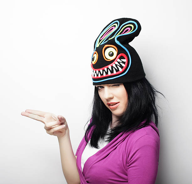 Playful young woman in funny hat with rabbit, studio shot