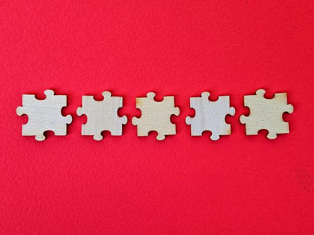 istock Five puzzle pieces arranged in a straight line along a vivid red background, creating a bold, minimalist composition. The image evokes teamwork, connection and problem solving in a modern visual 2245661352