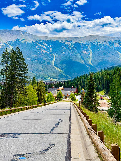 istock Mountain highway descends toward alpine valley with distant peaks under clear midday sky — forward motion 2245662327