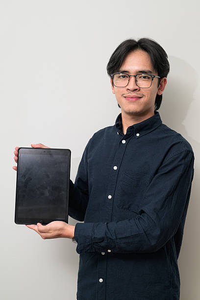 Portrait of handsome young Asian Thai man wearing eyeglasses using digital tablet computer
