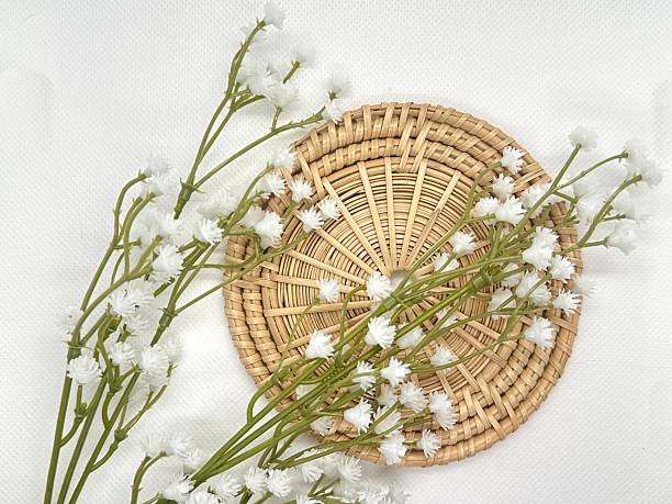 istock Delicate white flowers arranged elegantly on a round woven basket, creating a natural and aesthetic display on a soft textured background. 2245676490