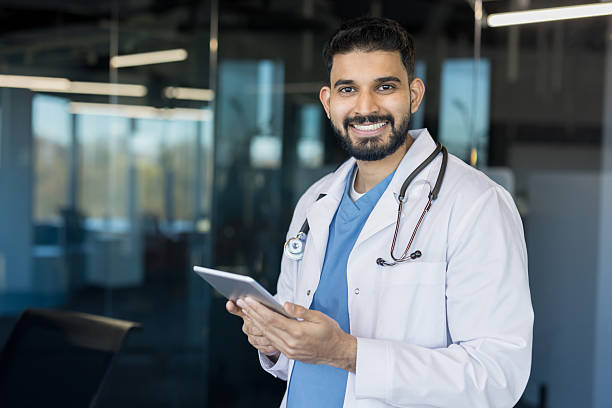 istock Indian doctor smiling, holding digital tablet in modern clinic 2245680053