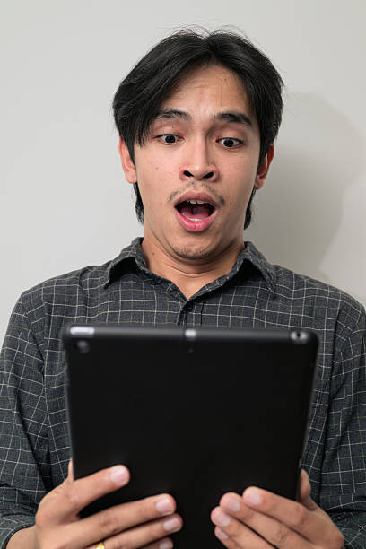 istock Portrait of handsome Young Asian Thai man using digital tablet computer against white background 2245680408
