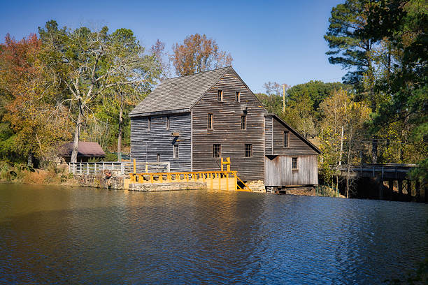 A nice landscape in Autumn of the historical timber watermill viewed over the still pond waters at Yates Millpond Park in Raleigh, North Carolina in the Eastern United States.