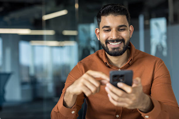 istock Indian businessman using mobile phone smiling and texting 2245685968