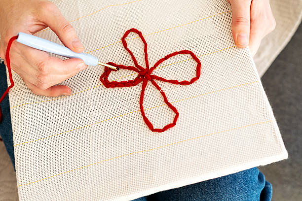 istock Hand crafting a red flower design on fabric using crochet technique for relaxation and creativity 2245691074