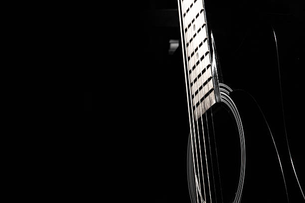 istock black acoustic guitar on a black background, silhouette 2245698916