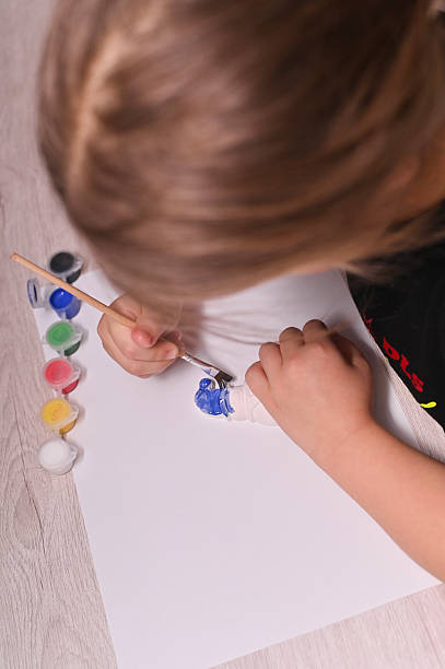 istock vertical. girl paints a plaster figure with bright colors. 2245719064