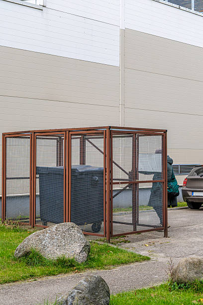 istock Secured Waste Containers in Metal Cage Next to Modern Building 2245719434