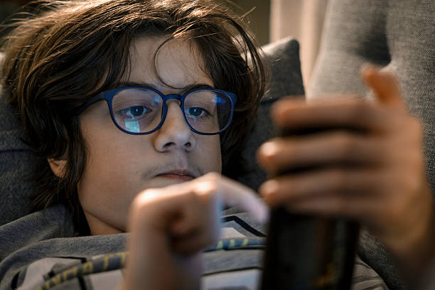 istock Young boy wearing glasses scrolling smartphone 2245720949