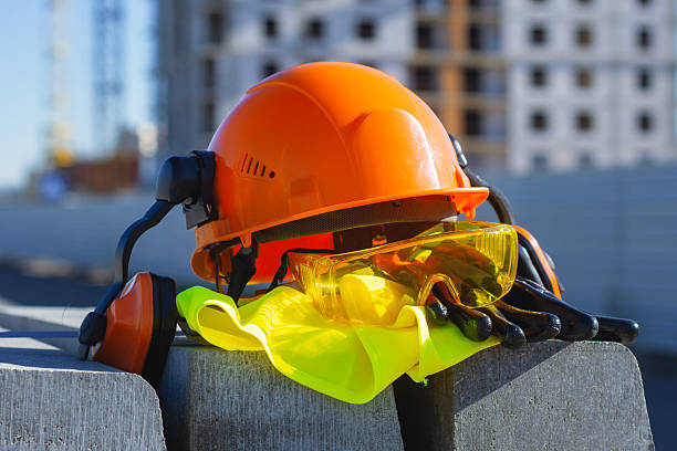 istock Construction safety equipment including a hard hat, protective gloves with goggles and ear defenders lies on a construction site. Concept workplace safety, industrial protection and gear. 2245727621