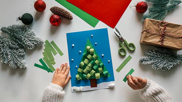 istock Child's handmade Christmas tree card with decorations and gifts on a white table 2245728187