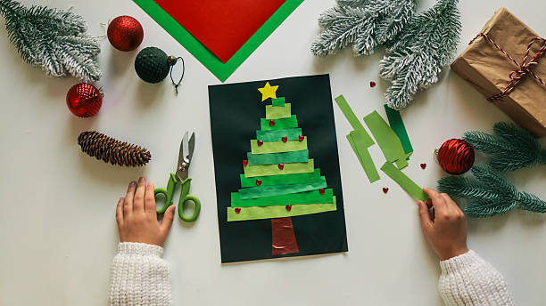 istock Christmas tree craft with paper, scissors, and festive decorations on white 2245728192