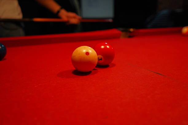 istock Close-up of two billiard balls on a red pool table, featuring a white cue ball with red dot and a red number three ball 2245730572