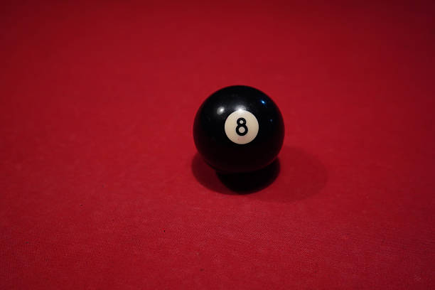 istock Black 8-ball on red billiard table under focused lighting 2245730781