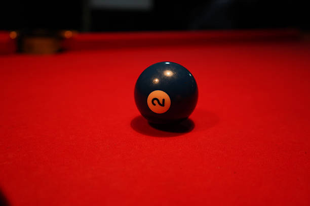 Blue number two billiard ball on a red pool table with other balls in the background