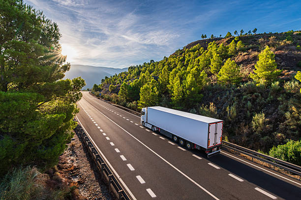 istock Refrigerated truck driving on a two-way road atop a mountain bordered by forest 2245732460