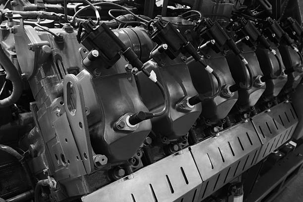 Large  piston gas engine electric generator with many valves and pipes. engine is orange and has many valves.