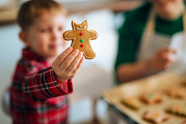 Child eating handmade Christmas cookies during baking at home.