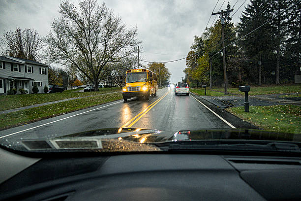A bright yellow school bus is approaching from the opposite direction as this car travels along a stormy, rainy, rural western New York State highway in early November.