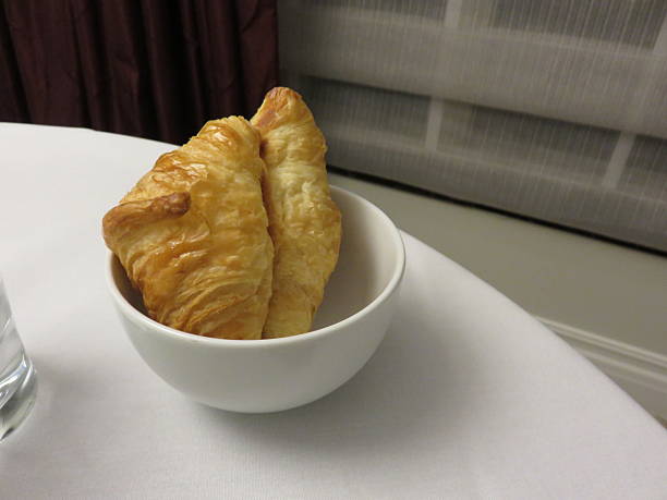 Two croissants in bowl on white table cloth