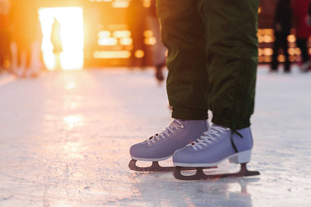 Ice skating on the ice rink arena with people, skating rink surface, ice skating in winter city, winter activities, holiday christmas time, with new year decoration and illumination, ice skates boots stock photo