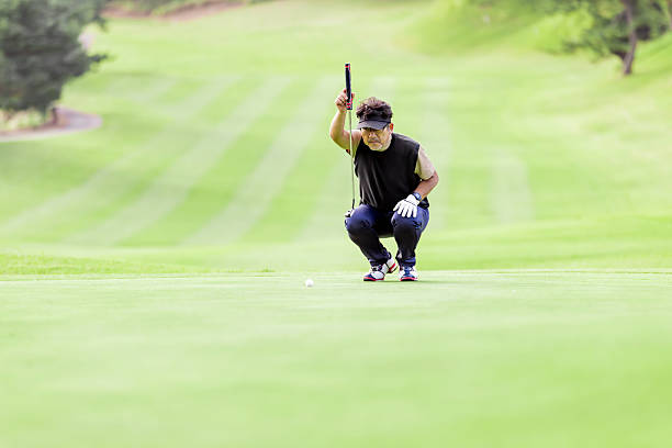 Young Caucasian female golfer placing a golf ball on the tee box, preparing for her drive with focused determination on a sunny day at the golf course.
