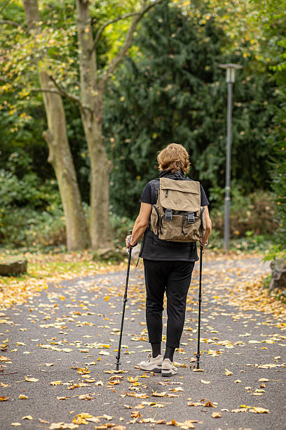 istock Hiking through a tranquil autumn park with a backpack and walking poles 2245750046