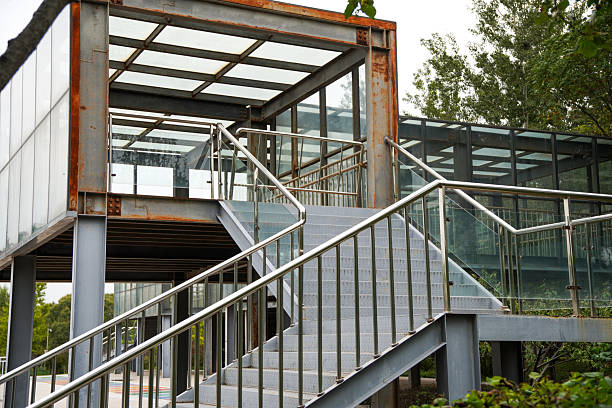 A modern structure with steel framework and glass panels features a metal staircase with railings, suitable for outdoor urban settings.