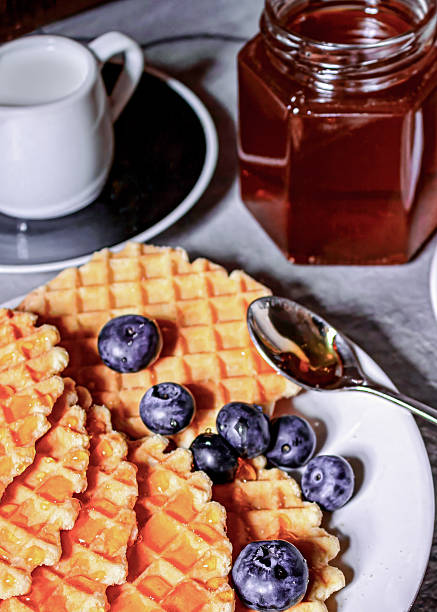 Breakfast on the table, a cup of coffee and waffles, blueberries and honey
