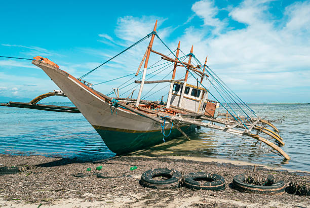 istock Beached wooden boat on sandy shore with tires 2245775398