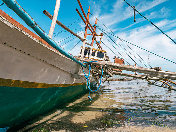istock Traditional fishing boat rests on shore during low tide 2245775423