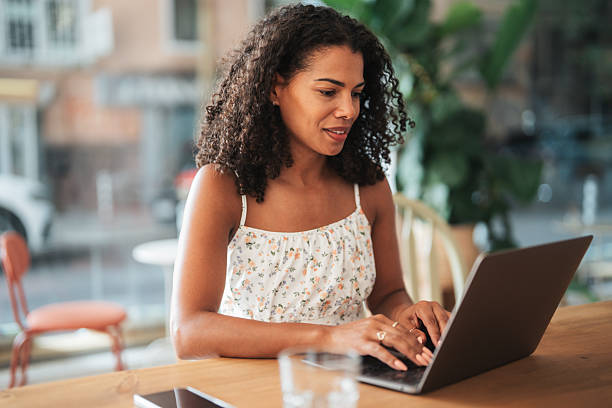 istock Young woman working in a cafe, using laptop and smiling at camera 2245787663