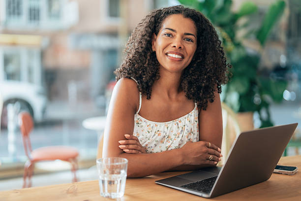 istock Young woman working in a cafe, using laptop and smiling at camera 2245787671