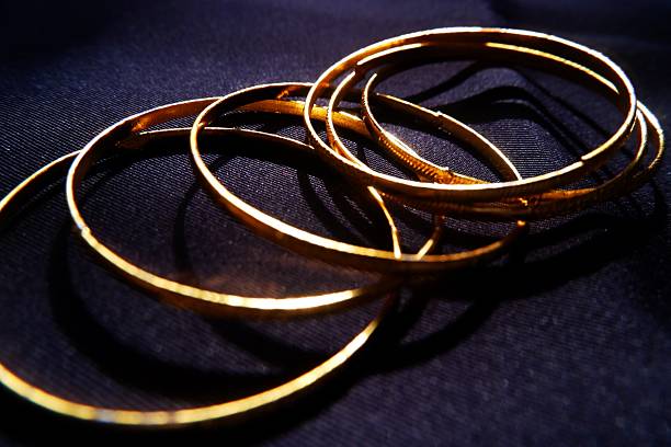 istock Minimalist Jewelry Composition  Shiny Gold Bangles on Black 2245791531
