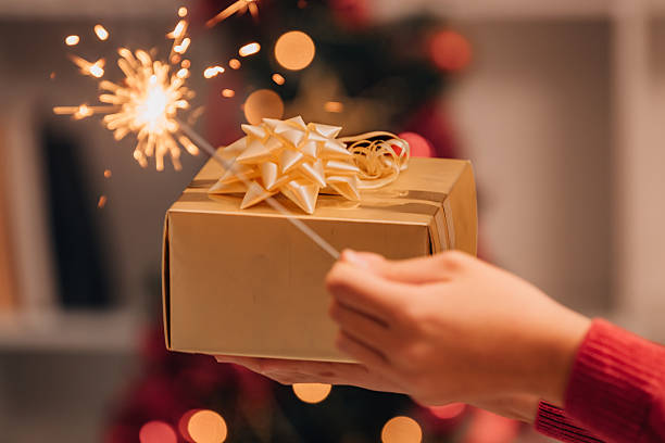 istock child's hand holding a Christmas gift and a sparkler 2245795881