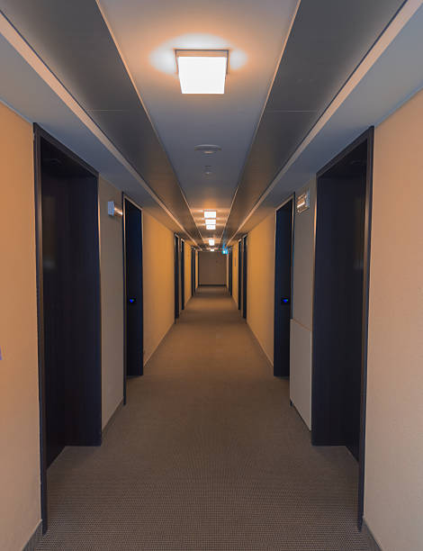 istock Modern hotel corridor with warm lights and open room doors 2245797920