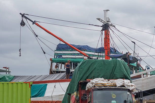 Jakarta, Indonesia - November 8, 2025 : Traditional wooden cargo ship with workers on deck preparing loading ropes at Sunda Kelapa port.