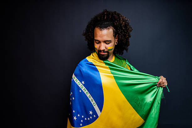 istock Young man wrapped in a Brazilian flag in a studio shot 2245804251