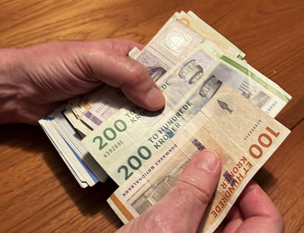 istock Mature Man Counting Danish Banknotes at Teak Table 2245805217