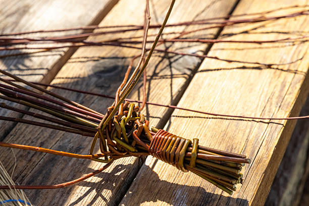 Willow branches being woven into a handmade craft on a wooden table