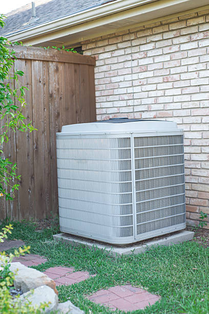 istock Suburban home with shingle roof, gutter and central air conditioning unit placed on concrete pad brick siding and wooden fence in Coppell, Texas. Red stepping stones, vining plant, suburbs Dallas 2245808222
