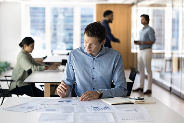 istock Pensive young businessman review statistic data in charts graphs 2245813544