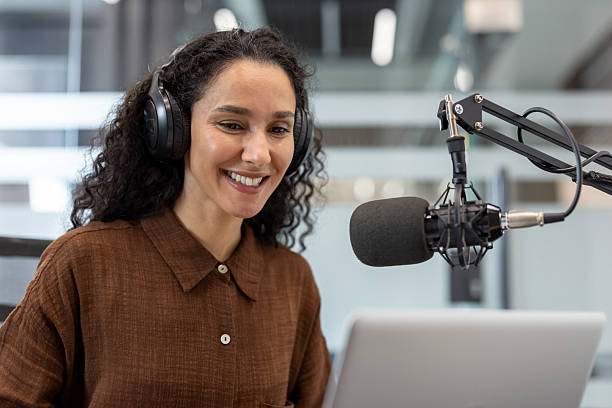 istock Smiling podcaster recording audio with a microphone and headphones in modern studio 2245817507