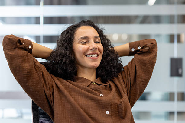 istock Smiling woman relaxing while sitting at her workplace in a modern office 2245817531