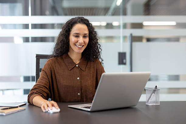 istock Smiling professional working at desk on a laptop in a modern office space 2245817537