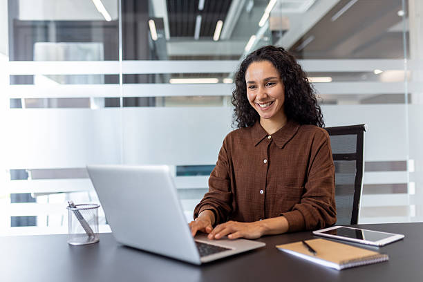 istock Smiling professional woman working on a laptop in a modern office environment 2245817546