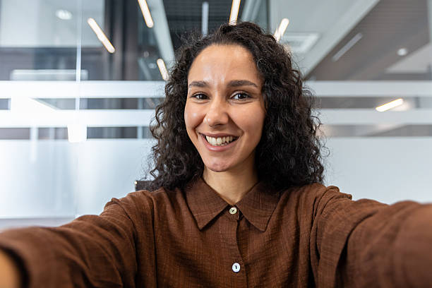 istock Smiling woman takes a selfie in a modern office environment 2245818045