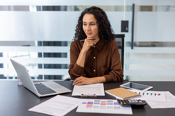 istock Focused professional woman working on documents at an office desk 2245818063
